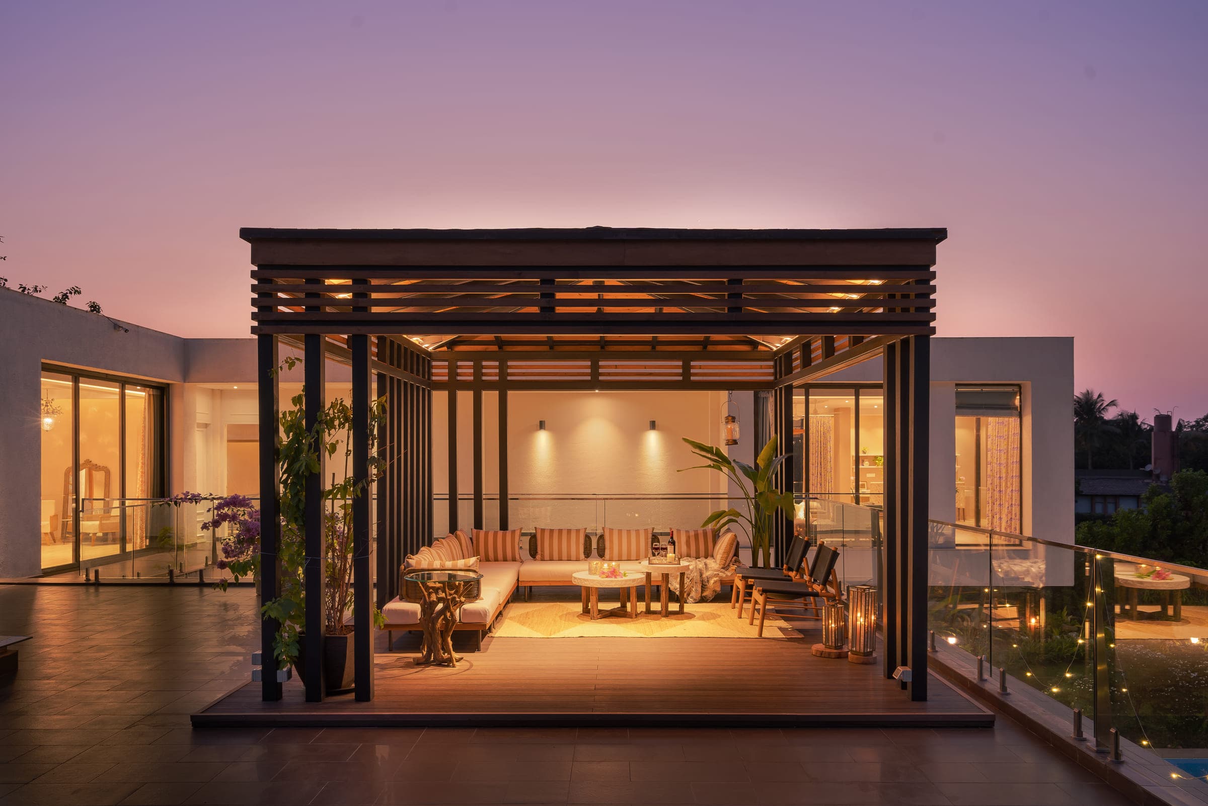 The rooftop pergola at dusk, its timber slats lit from beneath and seating arranged along its length.