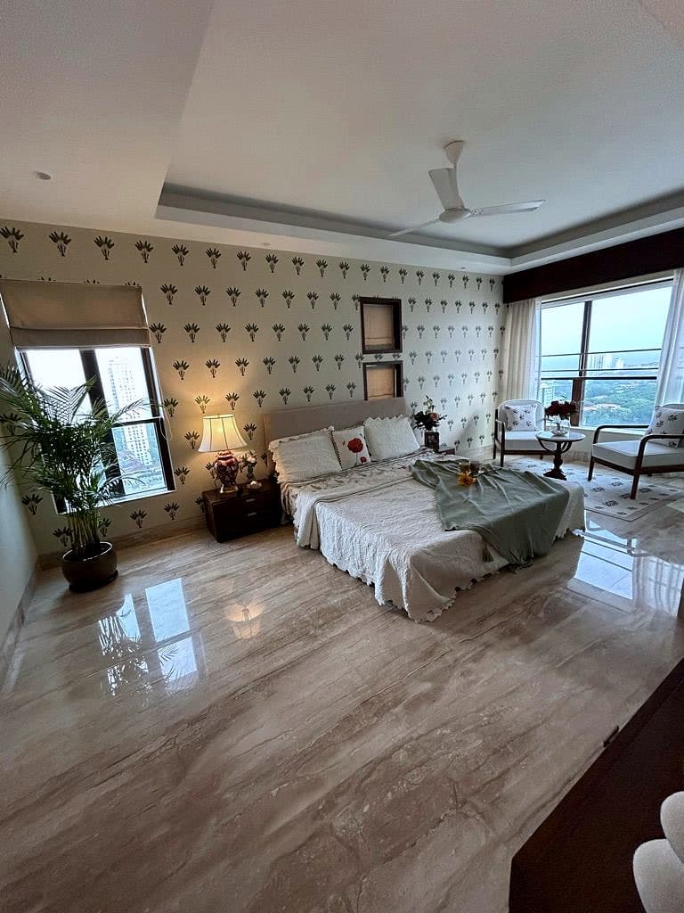 A bedroom papered in a small block-printed motif, marble underfoot and city windows on two sides.