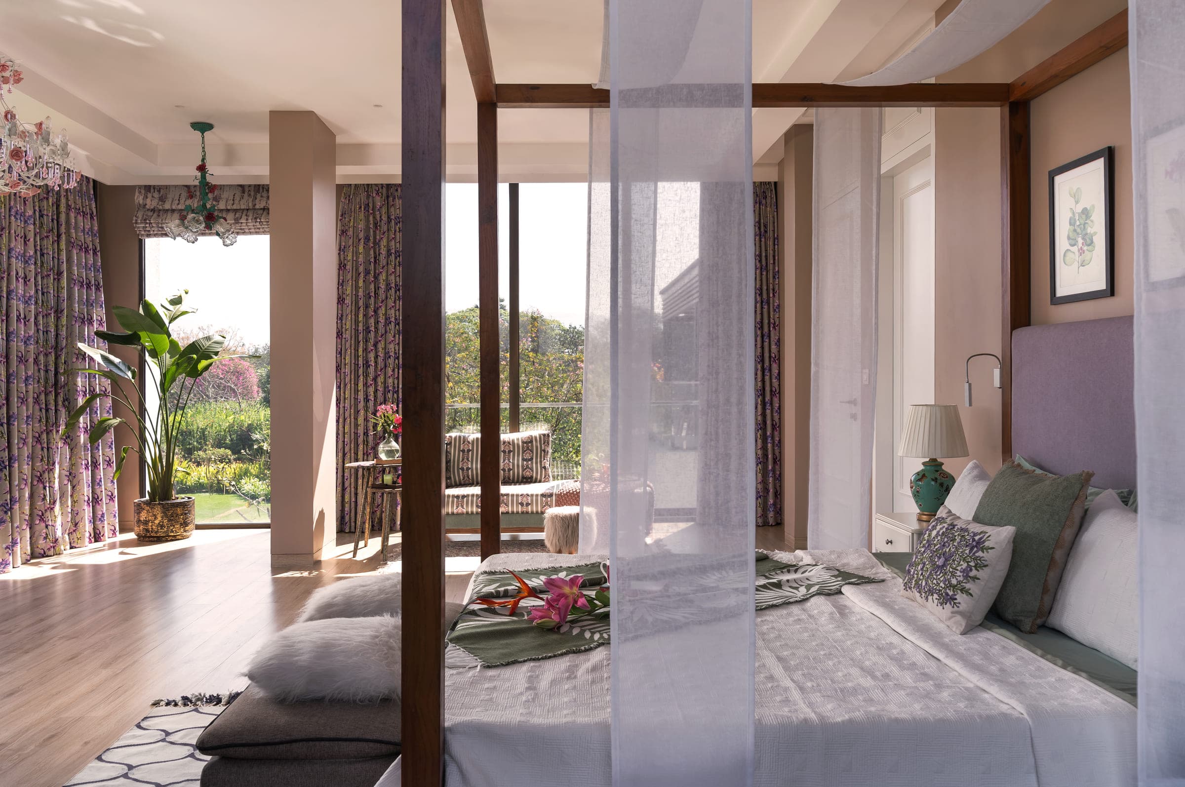 A timber four-poster bed draped in sheer white cotton, garden visible through the glazing beyond.