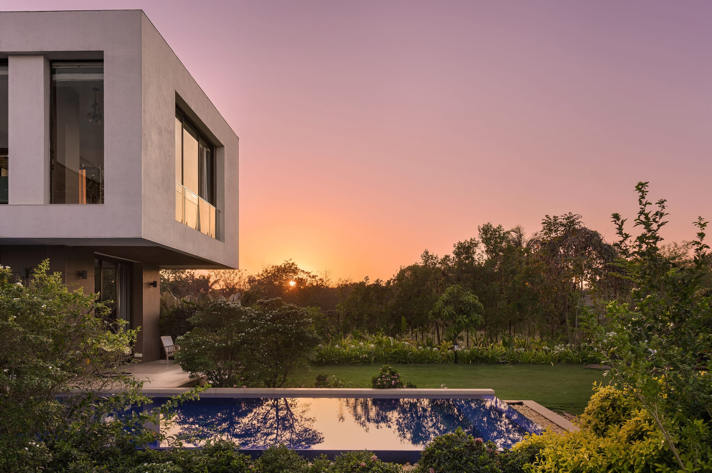 The pool at sunset, the sky above the garden turning orange and the house in silhouette along one side.
