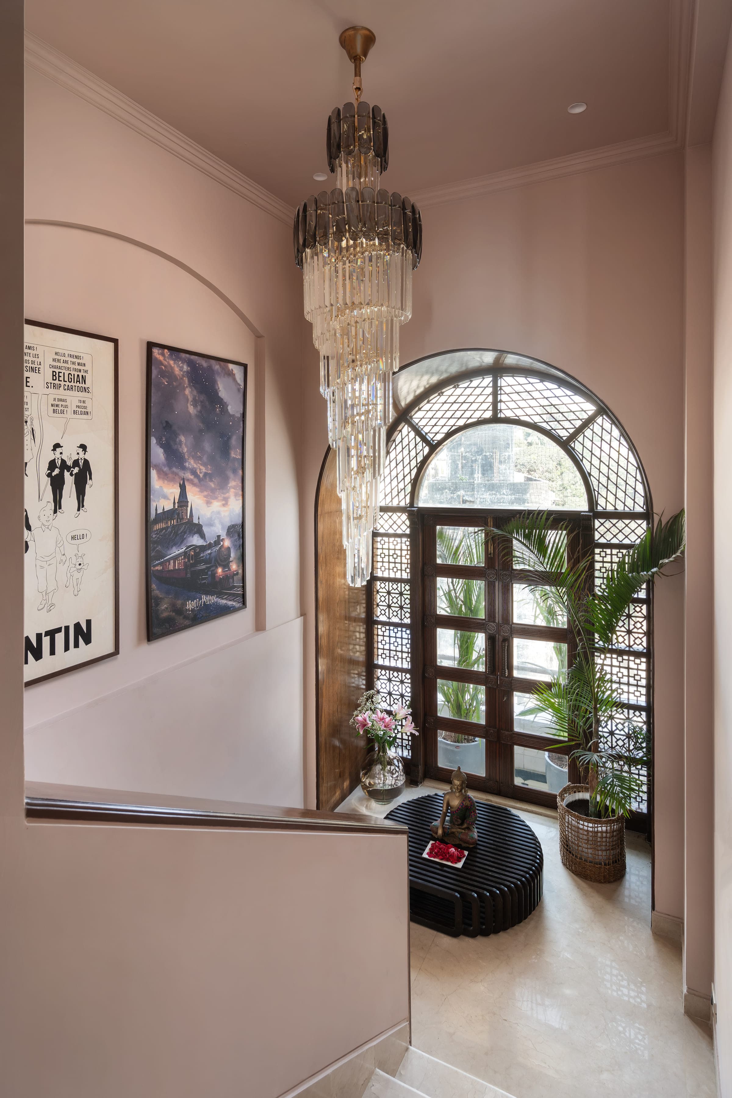 An arched window fitted with a dark timber jali screen, filtering light into the blush living room.