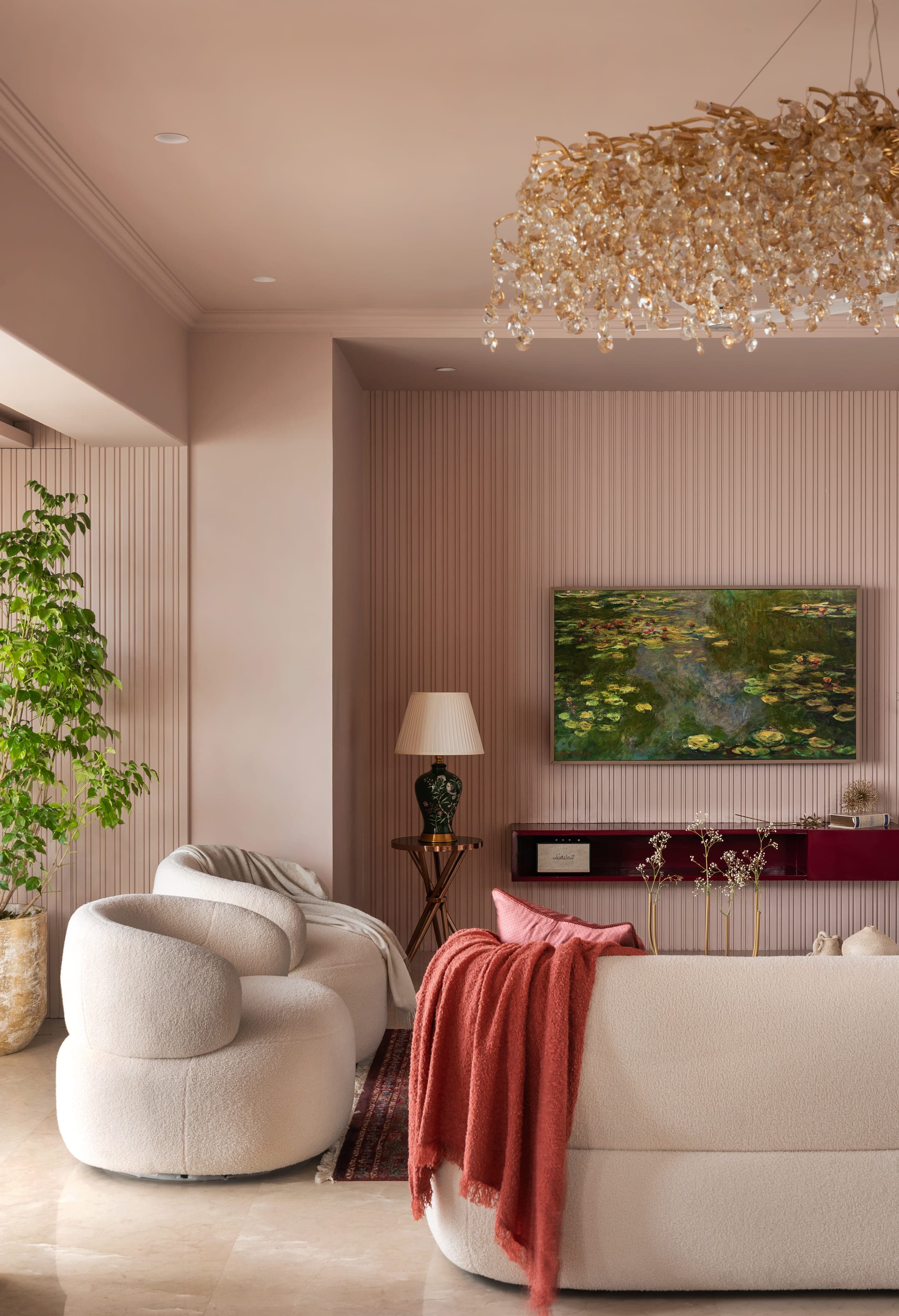 A fluted blush wall with a lotus painting above a low burgundy lacquered console, a tall plant to one side.